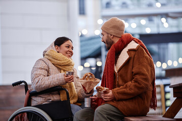 Portrait of smiling young woman with disability chatting with boyfriend on date outdoors in winter