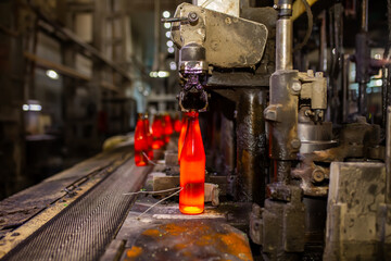 Glass factory, production of glass containers. Molten glass is blown into molds. Robotics in industry. Modern technologies, robotic machines produce products. Technological work at the plant.