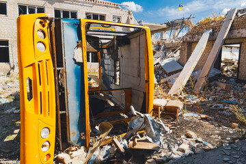 A destroyed yellow school bus in the yard of a destroyed school. War in Ukraine