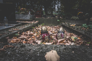 simple grave with burning candles covered by autumnal leaves, sadness and loneliness