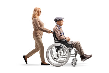 Full length profile shot of a woman pushing a senior man with disability in a wheelchair