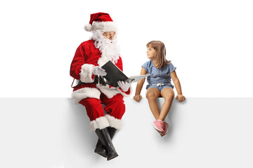 Santa claus sitting on a blank panel and reading a story to a little girl