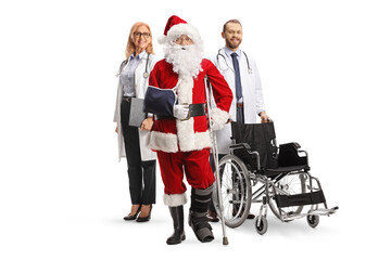 Injured santa claus with a foot brace and arm sling standing with a male and female doctors with a wheelchair