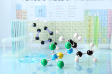 Molecular model and laboratory glassware on light surface