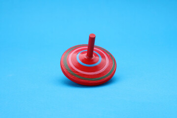 Fototapeta na wymiar One bright spinning top on light blue background. Toy whirligig