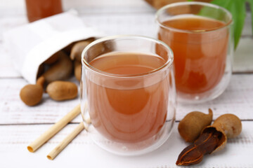 Tamarind juice and fresh fruits on white wooden table, closeup