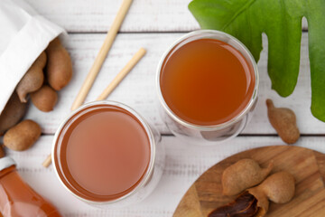 Tamarind juice and fresh fruits on white wooden table, flat lay