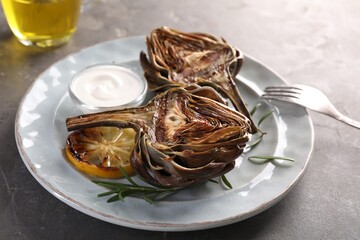 Plate with tasty grilled artichoke served on grey table, closeup