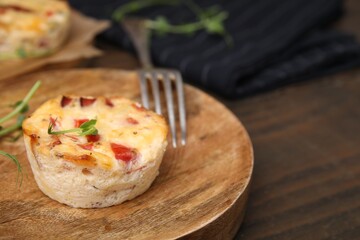 Delicious egg muffin with cheese and bacon on wooden table, closeup. Space for text