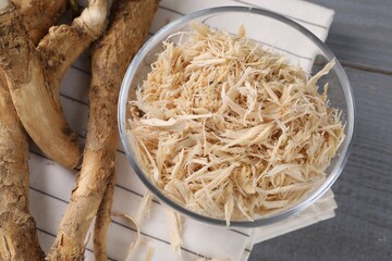 Grated horseradish and roots on grey wooden table, above view