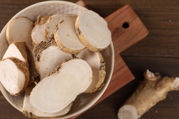 Cut horseradish roots on wooden table, top view