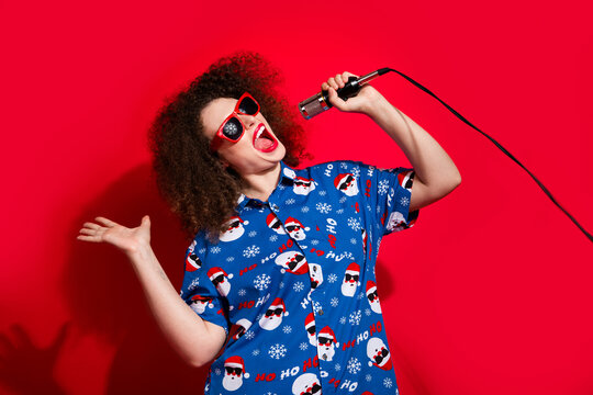 Photo portrait of attractive young woman dancing funky singing mic wear trendy blue print x-mas clothes isolated on red color background