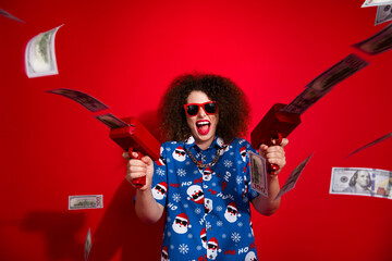 Photo of cheerful funky woman wear ugly santa claus print x-mas shirt shooting lottery cash flying...