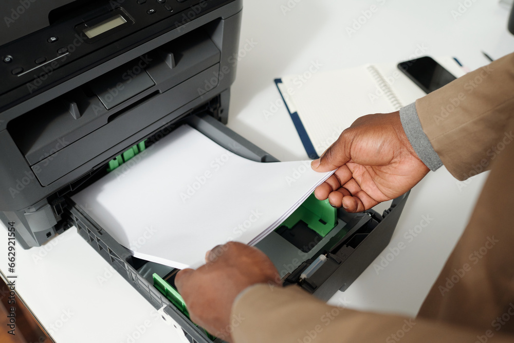 Poster close-up of hands of young male white collar worker preparing for copying documents while putting st