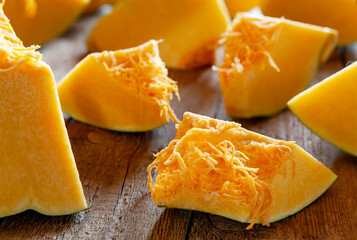 Fresh organic raw sliced pumpkin on wooden background, selective focus, close up