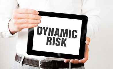 Text DYNAMIC RISK on tablet display in businessman hands on the white background. Business concept