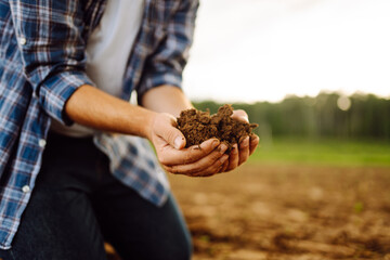 The soil is in the hands of an experienced agronomist. Close-up of a farmer's male hands checking the quality of the soil, the fertility of the land. A worker holds a plowed field of soil.