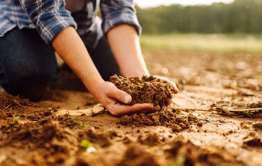 The soil is in the hands of an experienced agronomist. Close-up of a farmer's male hands checking the quality of the soil, the fertility of the land. A worker holds a plowed field of soil.