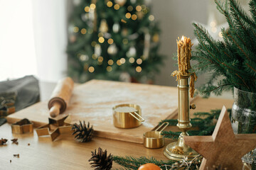 Vintage candle, wooden board, rolling pin, golden metal cutters, cooking spices and festive...