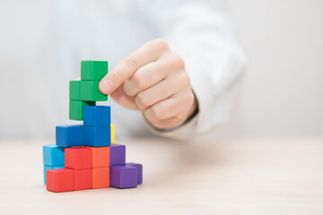 Man's hand stacking colorful wooden blocks. Business development concept