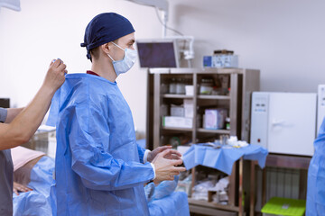 The nurse ties the doctor's gown before the operation, the surgeon during the operation