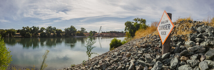 Panorama of levee with danger sign on Sacramento river 