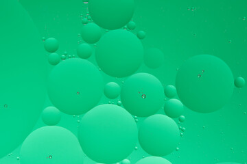 Macro photo with circles oil droplets water surface. Abstract green background with oil bubbles.