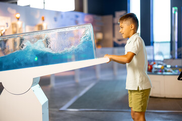 Little boy learns physics interactively on a model that shows physical phenomena while visiting a science museum. Concept of children's entertainment and learning