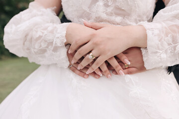 The groom hugs the bride and the hands of the newlyweds with wedding rings close-up. Beautiful bride's manicure and wedding rings close-up. Wedding day and wedding ceremony