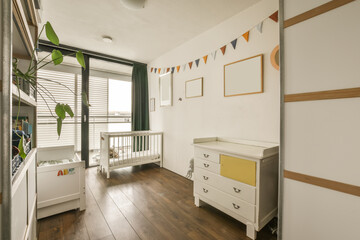 a child's room with wooden flooring and white walls, including a cribt bed in the corner