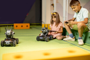 Kids playing with robotic cars controlling them with remote controls on a playground in science...