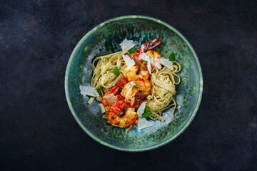 Traditional fried king prawns with Italian tagliatelli pasta and parmesan cheese served as top view on a design bowl with text space