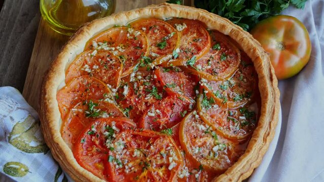Round puff pastry pie tart with tomato. Rotate.