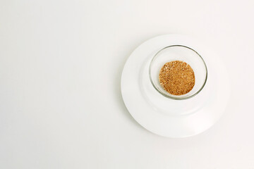 Dry ground ginger in a glass plate on a white background. Close-up.