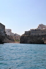  bridge over the beach, bay in Polignano a Mare, simple white buildings in the south of Italy, flat rocks on the coast, beach between the rocks, rocky coast
