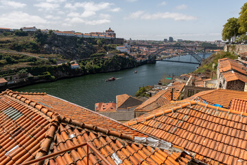 Widok na dachami z pomarańczowymi dachami na rzekę Duero oraz słynny most Ponte Dom Luís w Porto, stolicy Portugalii w Europie