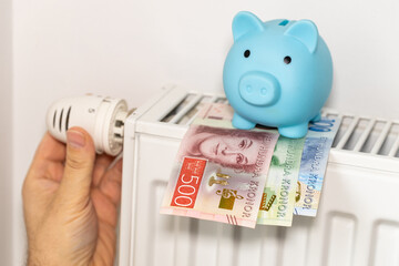 costs of heating apartments in winter in Sweden, Energy and economic concept, Hand unscrewing the radiator, piggy bank and Swedish krona - obrazy, fototapety, plakaty