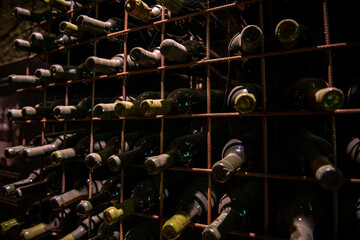 zakurzone butelki z winem leżakujące w piwnicy
