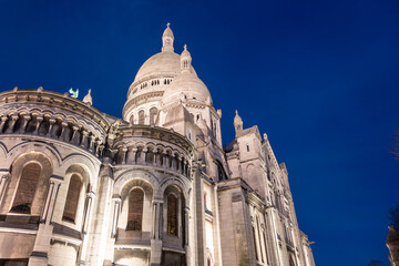 Obraz premium The Basilica of Sacre Coeur de Montmartre illuminated in the evening. Roman Catholic church and minor basilica in Paris dedicated to the Sacred Heart of Jesus. France