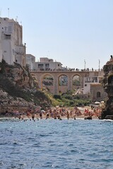  bridge over the beach, bay in Polignano a Mare, simple white buildings in the south of Italy, flat rocks on the coast, beach between the rocks, rocky coast