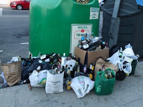 Alicante, Spain - October, 16, 2023: overloaded trash containers on Orihuela Costa streets next t oTM group residential complex on Playa Flamenca