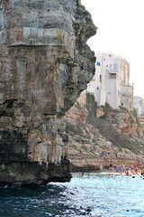 bridge over the beach, bay in Polignano a Mare, simple white buildings in the south of Italy, flat rocks on the coast, beach between rocks, rocky coast, large rocks falling into the sea