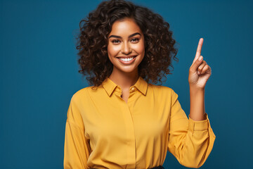 portrait of a expression of a happy laughing afro american woman with curly brown hair against colorful background who holds her index finger up to explain or point - obrazy, fototapety, plakaty
