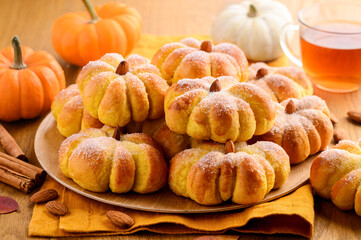 Obraz na płótnie Canvas Pumpkin spice bread buns with almonds and sugar on a wooden table. Autumn Halloween food concept. Selective focus