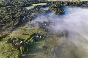 Rural landscape in Morning mist haze. Countryside at dawn in fog, aerial view. Country houses in Foggy dawn. Village in morning mist sunrise. Farm house in dusk at rural fog landscape. House in rural