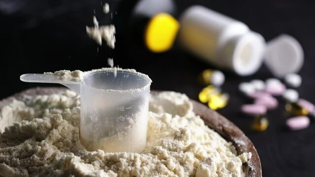 Pouring whey dry sport protein from above in slow motion, the supplements become nourishing food