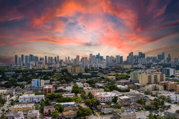 stunning aerial view with hotels, office buildings and skyscrapers in the city skyline, homes and apartments surrounded by lush green trees, cars on the street at sunset in Miami Florida USA