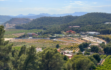 Fototapeta premium House in Spanish village. Village with country houses in an orange field. Agricultural field against backdrop of rural houses in mountains. Mountains landscape. Villa near mountain with farm field