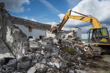 An excavator demolishes a building on a sunny day