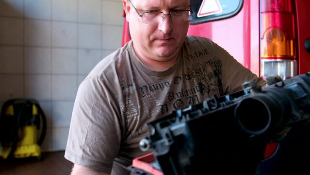 A Man with glasses Maintains an auto in a Garage. Auto Repair by an experienced Specialist in a vehicle Repair Shop. Replacing the oil and filter in the automobile. 4K video.